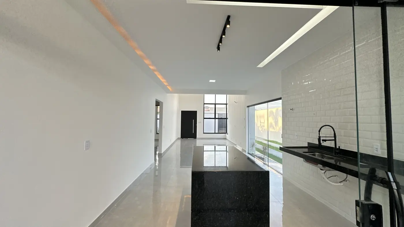 Sala e cozinha integradas na mesma enfiada, com piso claro polido e sanca iluminada.