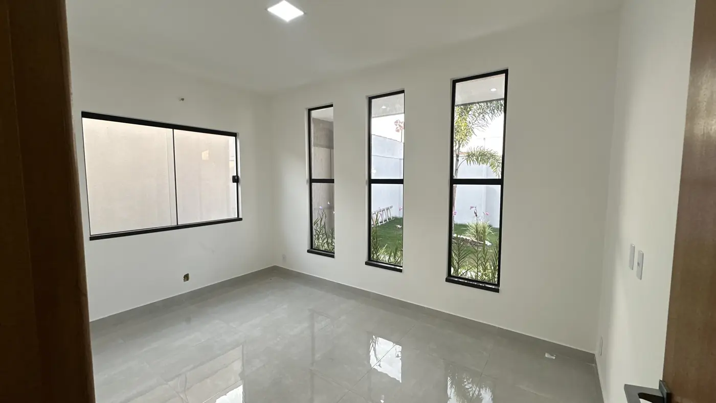 Quarto vazio com três janelas verticais estreitas e uma janela ampla, com piso claro polido.