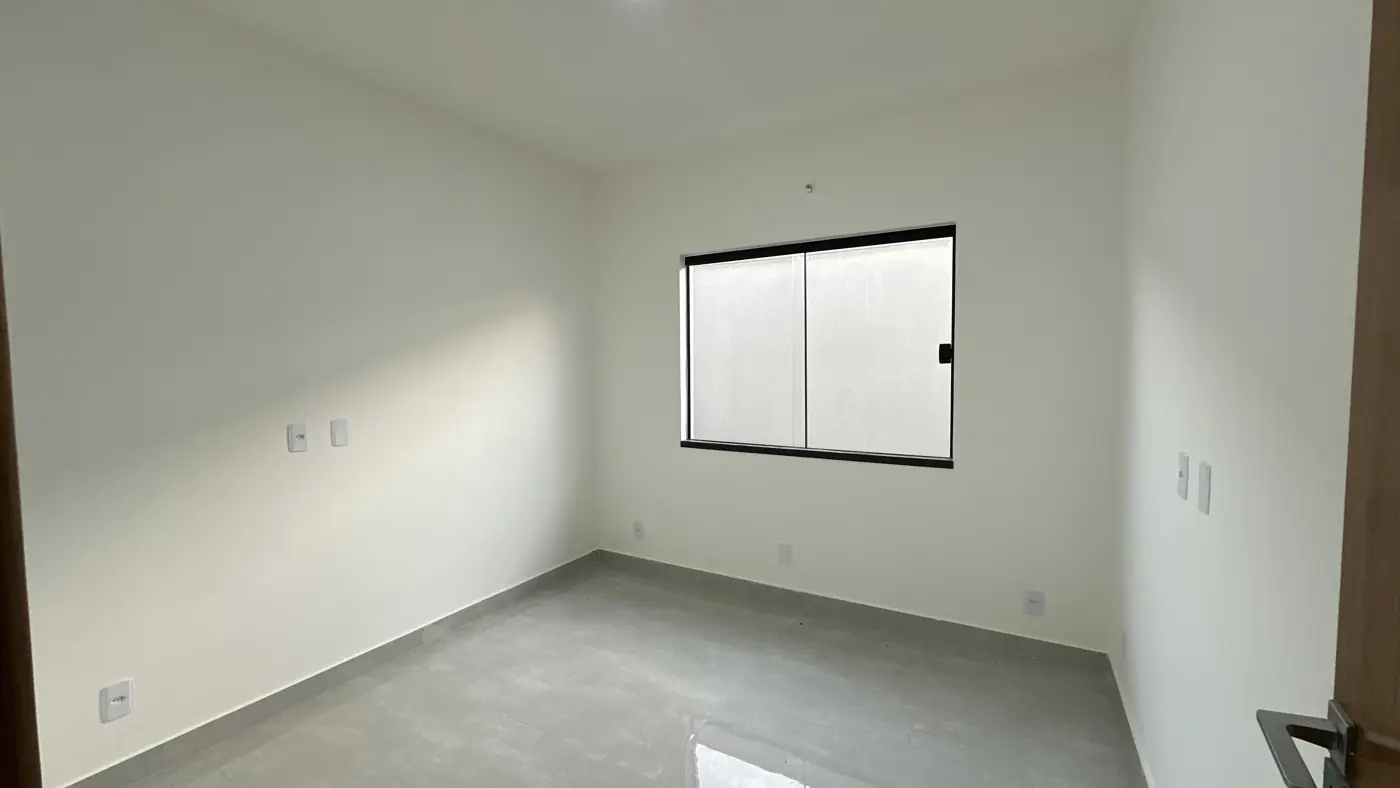Quarto vazio com janela de correr de esquadria preta e paredes claras.