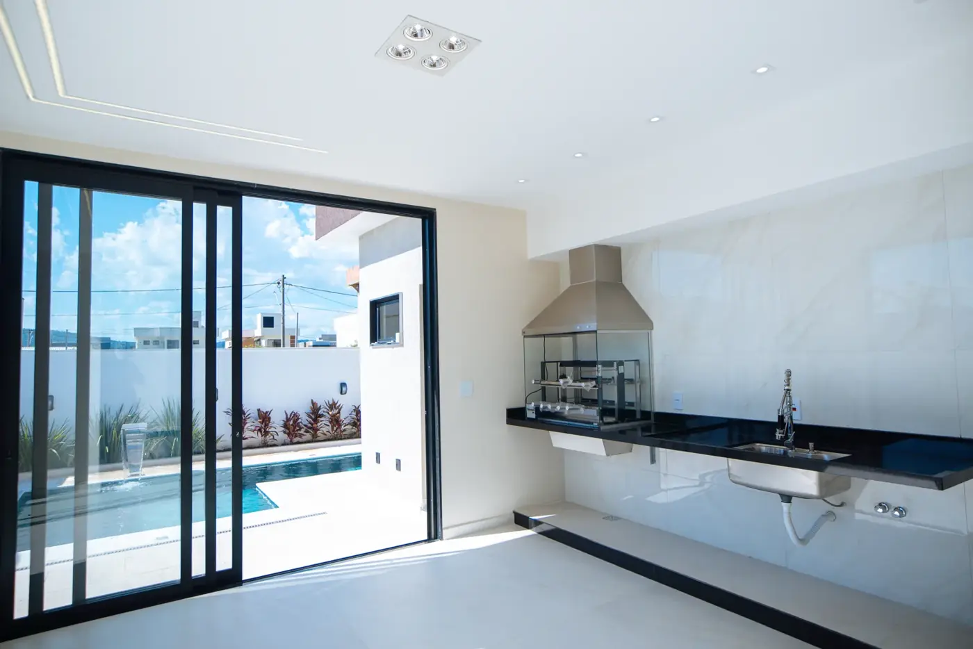 Varanda gourmet com churrasqueira embutida e vista para a piscina.