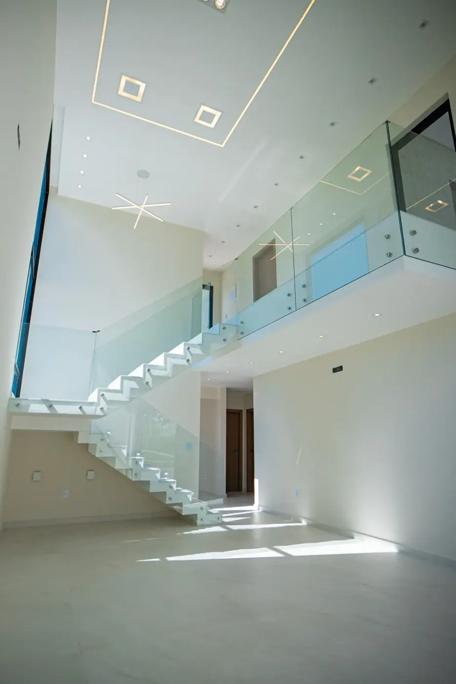 Mezanino do pavimento superior, com guarda-corpo de vidro sobre a sala.