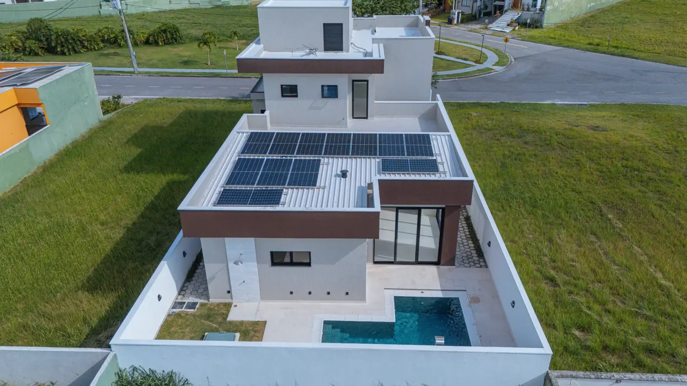 Vista aérea do lote, com as placas de energia solar no telhado, a laje superior e a piscina no quintal murado.